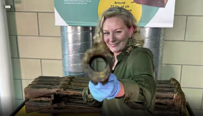 Donna Teasdale holding a preserved musket aiming it at the camera